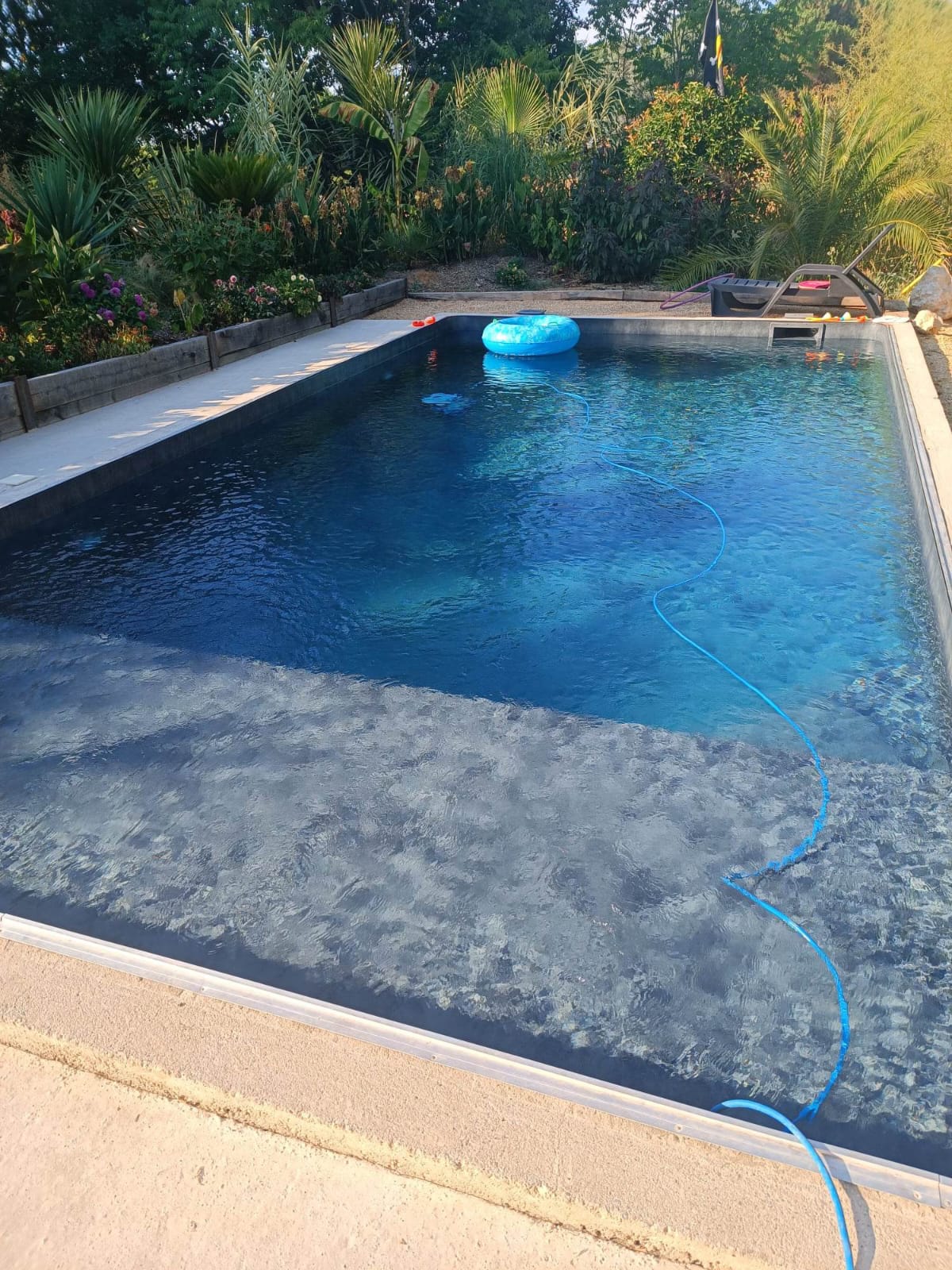 Cascade piscine moderne : ajoutez une touche de luxe en inox Lame d'eau en inox moderne déversant une cascade cristalline dans un jacuzzi à mosaïque bleue, créant une mousse rafraîchissante.