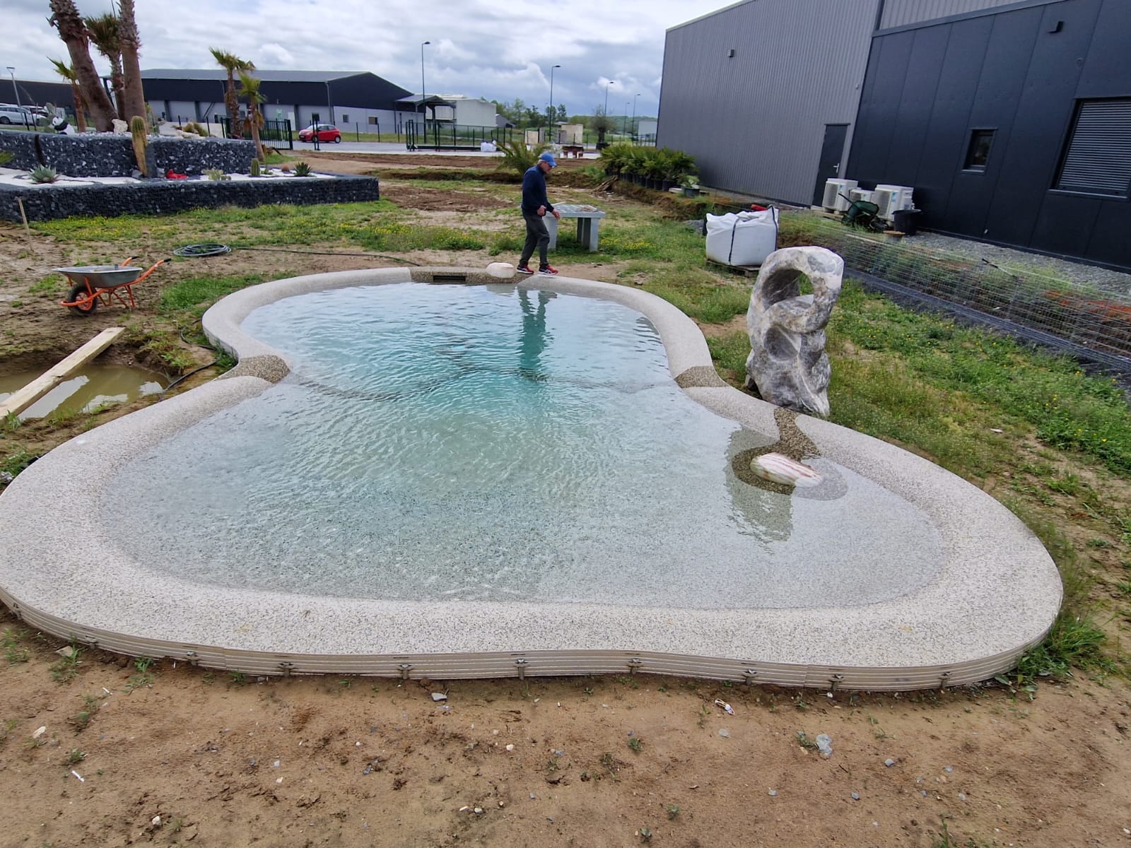 Cascade piscine moderne : ajoutez une touche de luxe en inox Lame d'eau en inox moderne déversant une cascade cristalline dans un jacuzzi à mosaïque bleue, créant une mousse rafraîchissante.